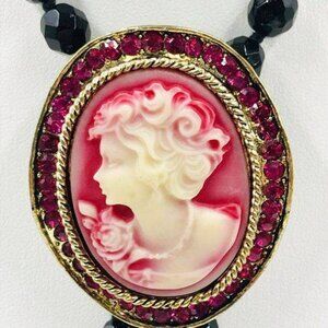 RED WAVY CAMEO BROOCH WITH PINK CRYSTALS ALONG THE PERIMETER.